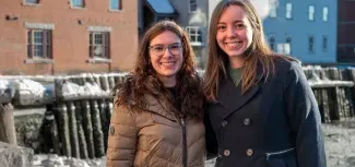 Two women pose in front of the Portland waterfront